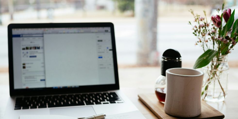 Ein Tisch auf dem ein aufgeschlagenes Buch vor einem offenen Notebook liegt