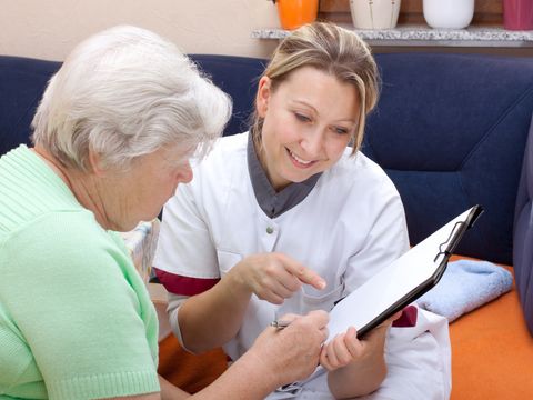 Altenpflegerin erklärt Seniorin ein Formular