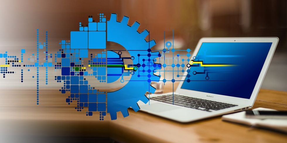 Ein Zahnrad befindet sich vor einem im Hintergrund stehenden Notebook