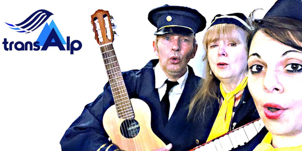 Drei Menschen, gekleidet wie Stewardessen und ein Pilot, stehen mit einer Gitarre und Keyboard zusammen. Links daneben ist das "transAlp"-Logo.