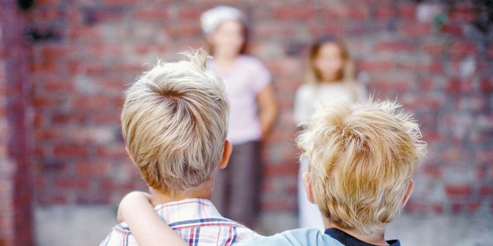 4 Kinder stehen an einer Mauer und spielen