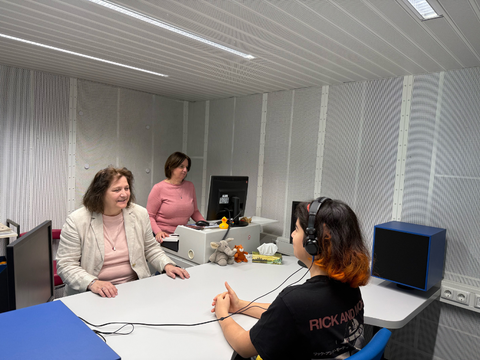 Zwei Mitarbeiterinnen führen einen Hörtest bei einem Jugendlichen durch.