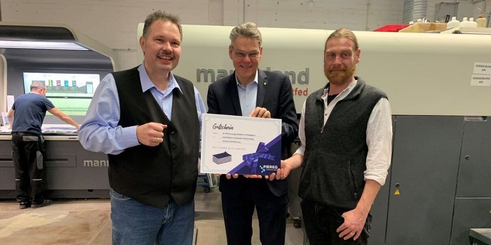 Gruppenbild von drei Männern in einer Produktionsanlage.