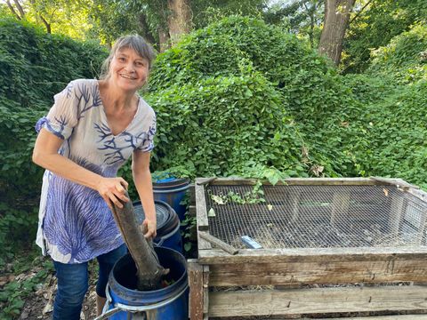 Frau verdichtet mit Holzstamm Essensrese in blauer Tonne
