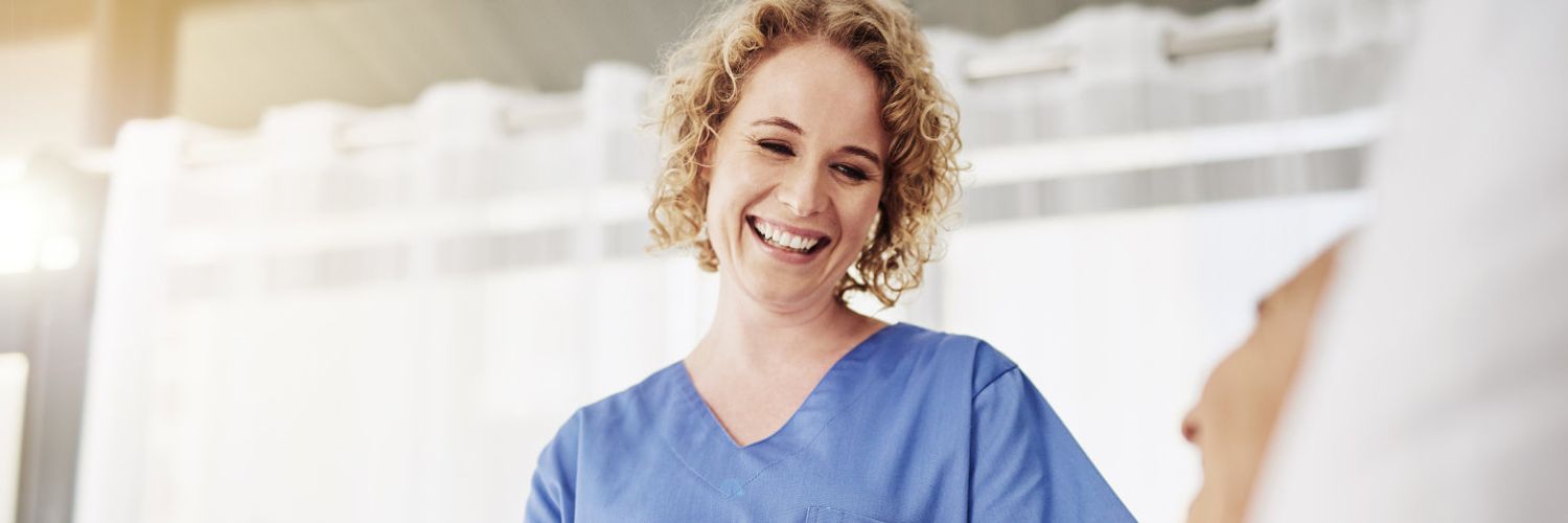 Eine lächelnde Krankenpflegerin spricht mit einem liegenen Patienten