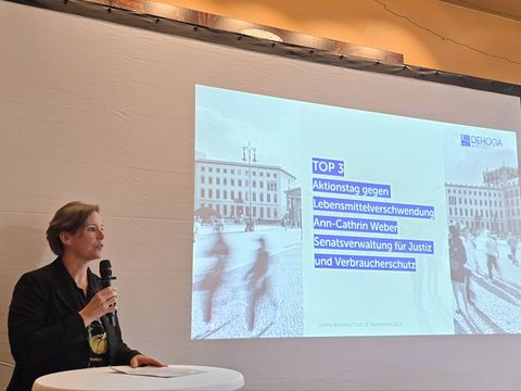 Ann-Christin Weber, Referentin für Ernährung, hält einen Vortrag, hinter ihr wird eine Powerpoint-Präsentation abgespielt