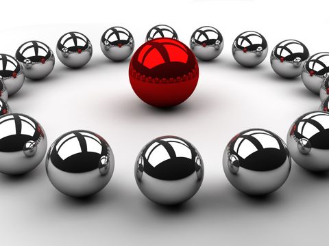 Viele Kugeln aus Chrom kreisförmig mit einer roten Kugel in der Mitte angeordnet