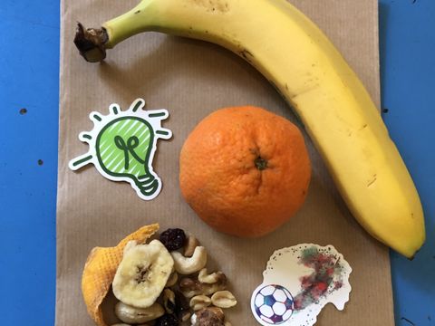 Banane Mandarine und Nüsse liegen auf einer Papiertüte