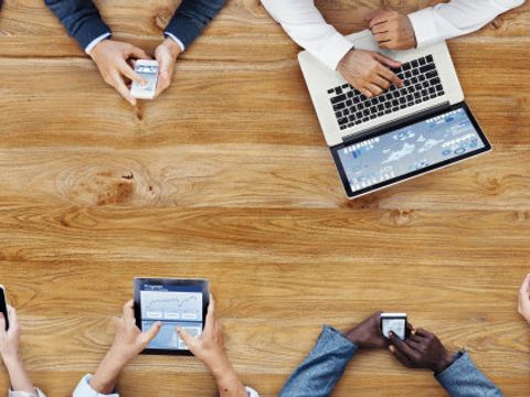 Blick von oben auf eine Gruppe von Menschen mit Tablets, Smartphones und Computern