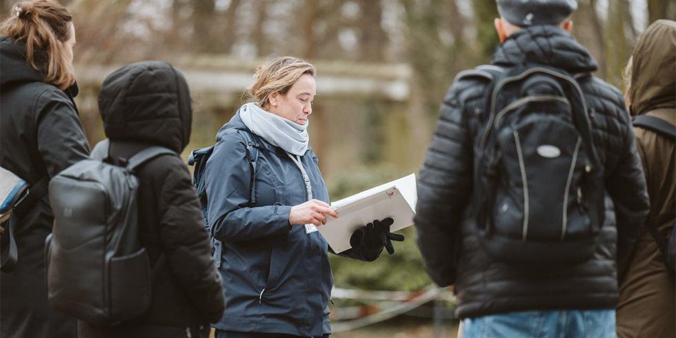 Swantje Glock mit Unterlagen umringt von einer Gruppe Menschen