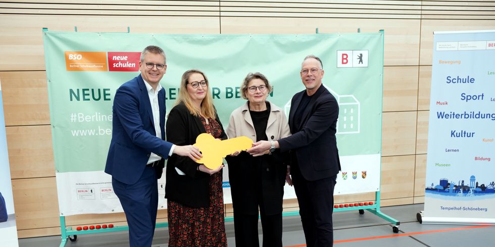 Zwei Frauen und zwei Männer halten einen großen Pappschlüssel