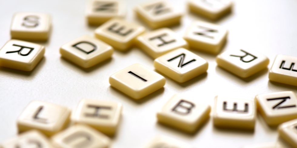 Spielsteine mit Buchstaben darauf, die ungeordnet auf einem Tisch liegen