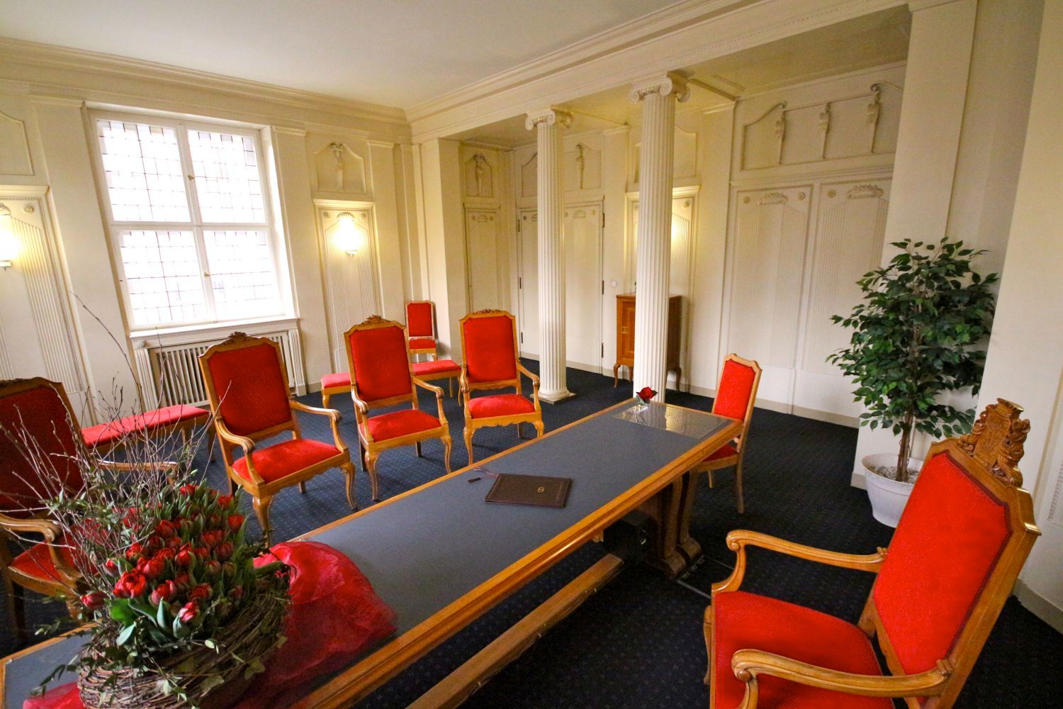 repräsentativer Raum mit rotgepolsterten Stühlen und Blumenschmuck