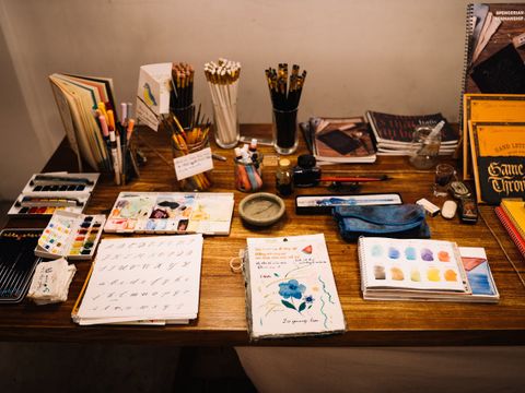 Bunter Malutensilien liegen auf einem Holztisch zur Buchverzierung
