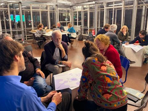 Gruppe gemeinsam am Tisch vor einem Plakat