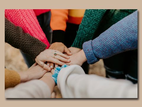 Mehrere Personen mit unterschiedlicher Hautfarbe legen ihre Hände übereinander
