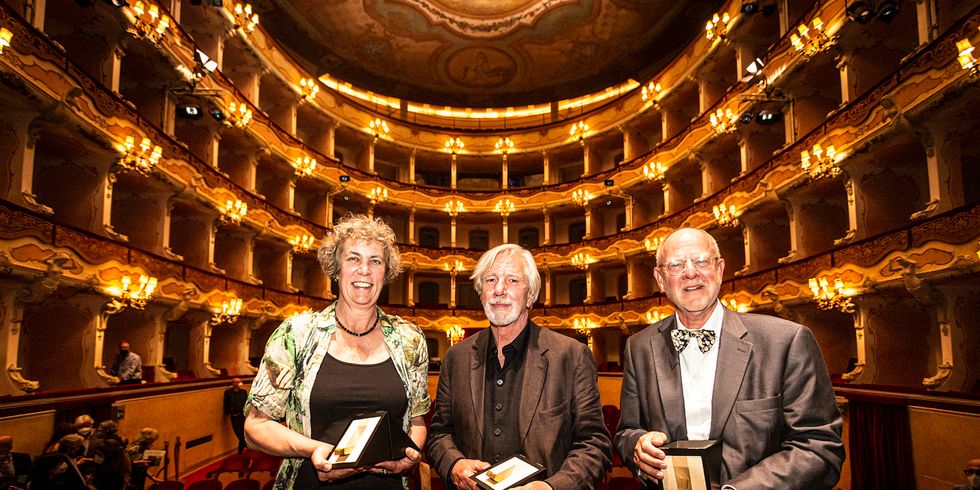 Zwei Männer und eine Frau in einem goldglänzenden Saal