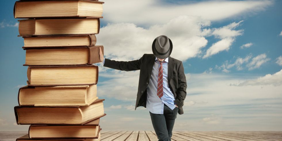 Ein Mann lehnt an einem großen Bücherstapel