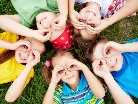 Im Kreis auf dem Gras liegende Kinder