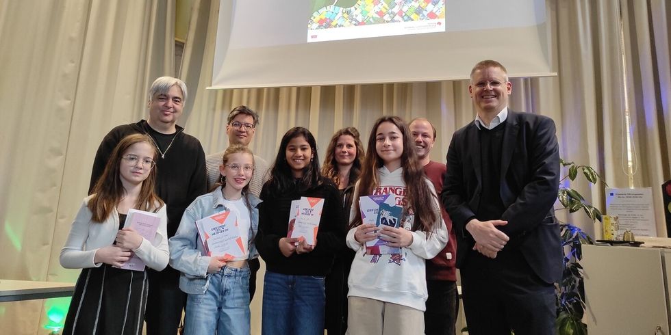 Vier Mädchen und fünf Erwachsene stehen nebeneinander und lächeln.