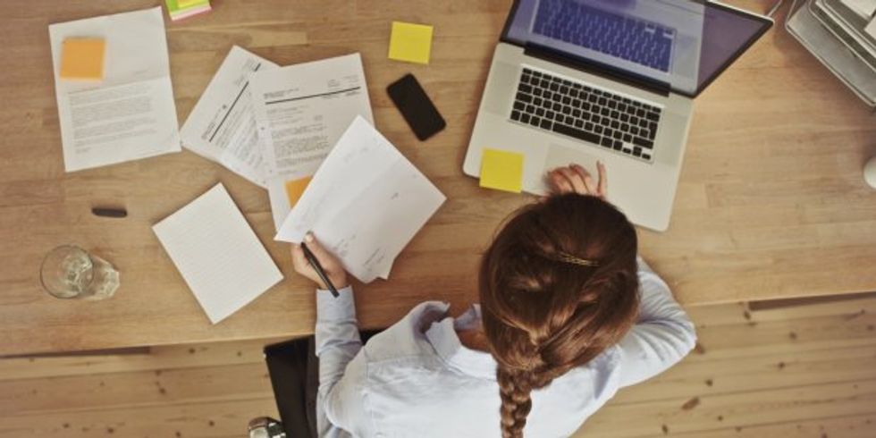 Frau arbeitend an ihrem Schreibtisch mit Dokumenten und Laptop