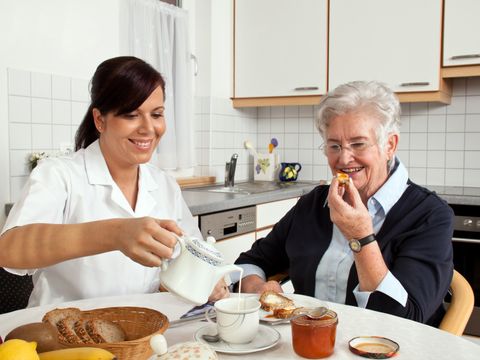 Eine Pflegerin frühstückt gemeinsam mit einer Seniorin