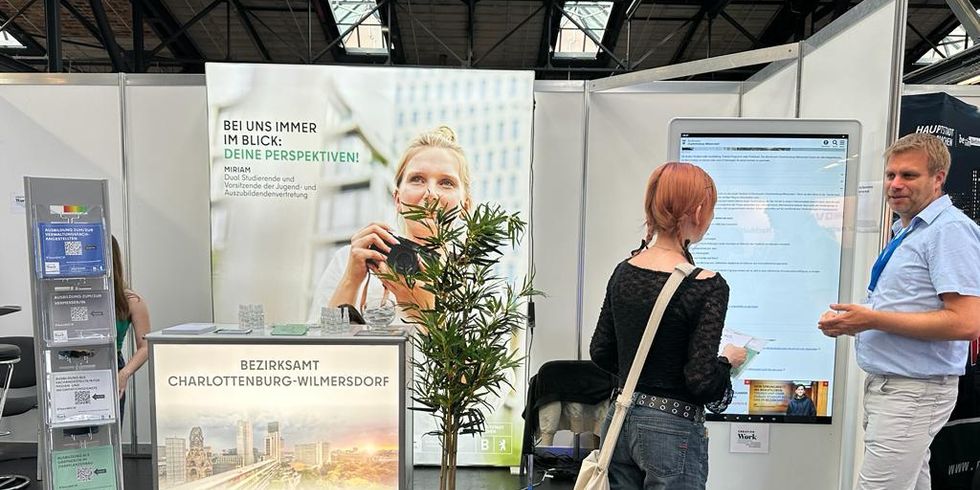 Erklären, was im Bezirksamt möglich ist: Oliver Lüning von der Ausbildungsleitung mit einer Interessentin vor der Digitalsäule