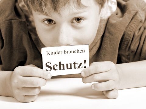 Junge mit Schild - Kinder brauchen Schutz