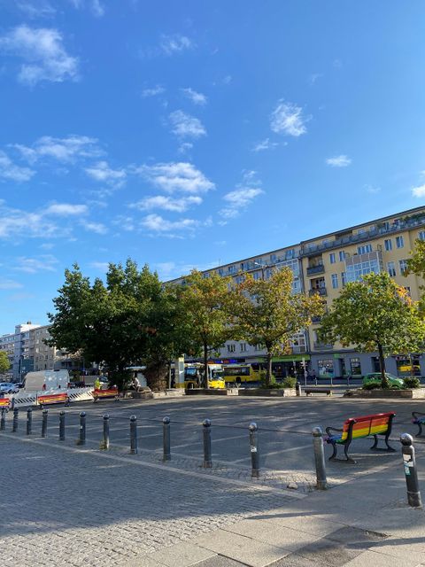 ein Platz mit Bäumen und farbigen Sitzbänken