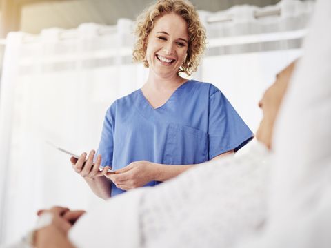 Eine lächelnde Krankenpflegerin spricht mit einem liegenen Patienten