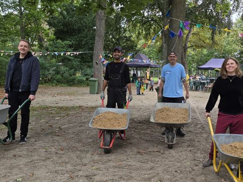 Bezirksbürgermeisterin Clara Herrmann (re) karrte gemeinsam mit Kessem und den Mitarbeitern des Nachbarschaftshauses Urbanstraße Sand auf den Spielplatz