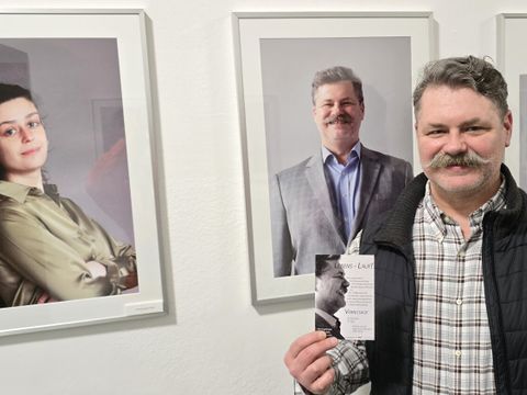 Fotografin Chloé Laurence Cohen (li.) und ein Mitschüler aus dem Berufssprachkurs zeigt vor seinem Portrait den Flyer der Ausstellung