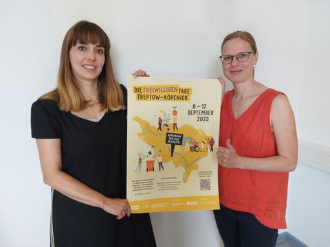 Carolin Weingart und Ute Clausner halten ein Plakat für die Freiwilligentage 2023 hoch