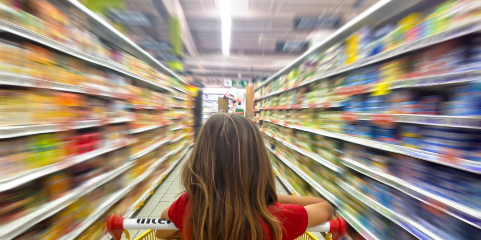 Junges Mädchen schiebt einen Einkaufswagen durch einen Supermarkt