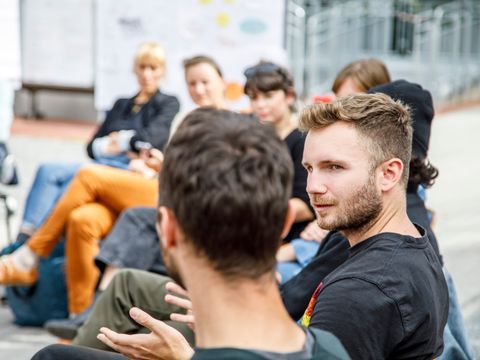 Menschen im Stuhlkreis draußen im zugewandten Gespräch