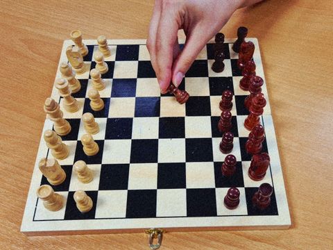 Hand bewegt eine Figur auf dem Schachbrett