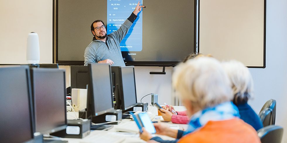 Kursleiter Andre Goslar erklärt am Whiteboard eine Smartphone-Einstellung