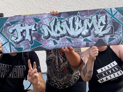 Drei Personen halten ein Banner mit der Aufschrift Jugendtreff no:name in die Höhe
