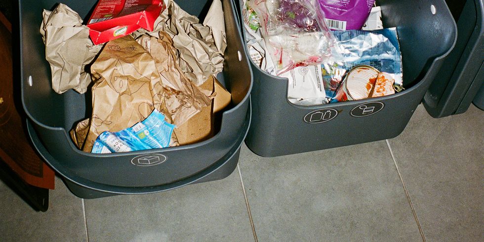 Behälter zur Mülltrennung in einer Küche mit Papiermüll und Verpackungen.