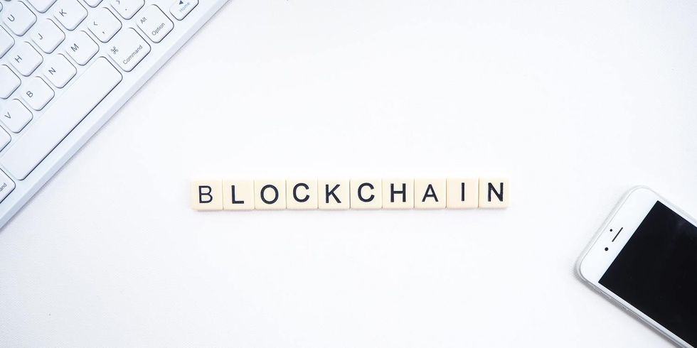 Blockchain buchstabiert mit Computertastatur und Mobiltelefon im Hintergrund