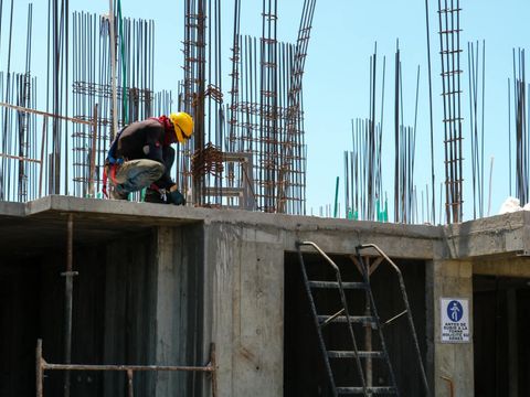 Ein Bauarbeiter auf dem Dach eines Hauses mit fehlendem Seitenschutz am Gerüst.