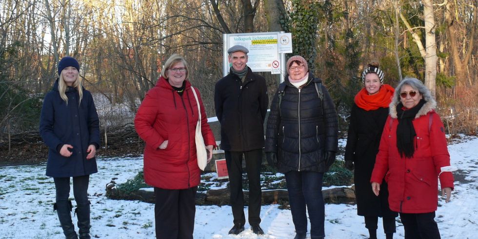 Sechs Menschen stehen auf einer Grünfläche im Schnee.