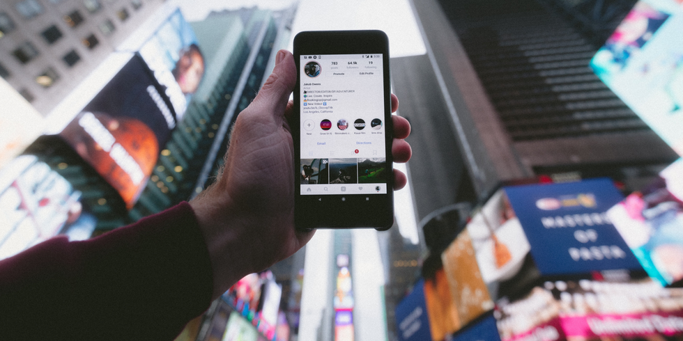 Smartphone vor mehreren elektronischen Großstadt-Werbetafeln