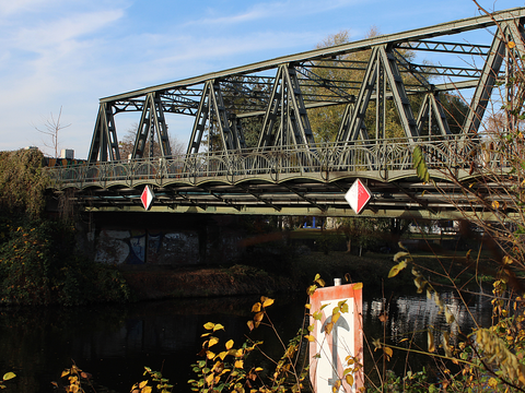 Aufnahme der Späthstraßenbrücke in Neukölln mit Uferanschnitt, Schifffahrtsschild und Zweige im Vordergrund