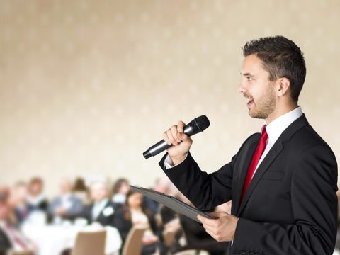 Redner mit Mikrofon vor einer Menschengruppe