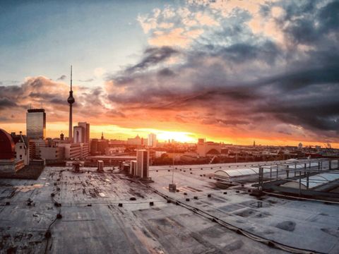 Sonnenuntergang über Berlin mit Fernsehturm und weiteren Häusern in der Ferne