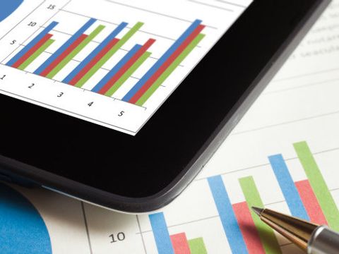 Statistische Aufbereitung auf Blatt mit Kugelschreiber und einem Tablet darüber liegend
