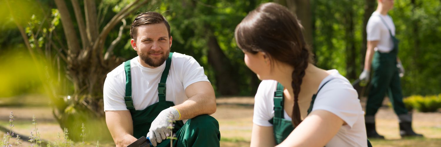 Eine Landschftspflegerin und ein Landschaftspfleger sprechen während der Arbeit