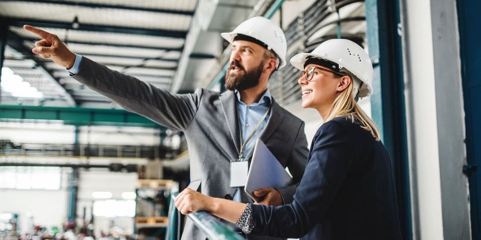 Mann und Frau mit Helm in einer Fabrik