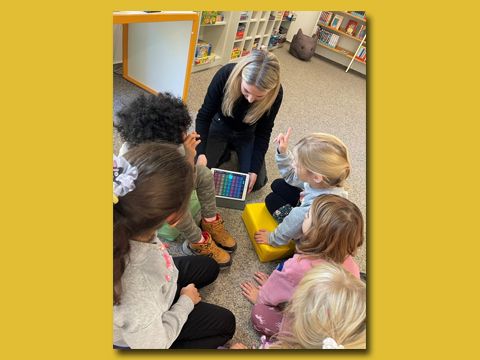 Frau liest knieend vor Kindern